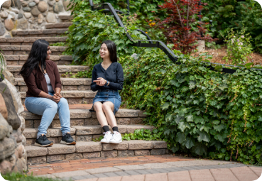 reports-page Two students sit on some steps outside