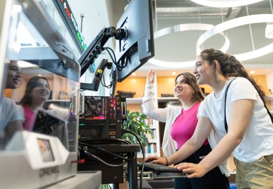 Two people examine an experimental setup at  The Bridge lab located in the Instructional Centre, University of Toronto Scarborough. (photo by Moussa Faddoul)